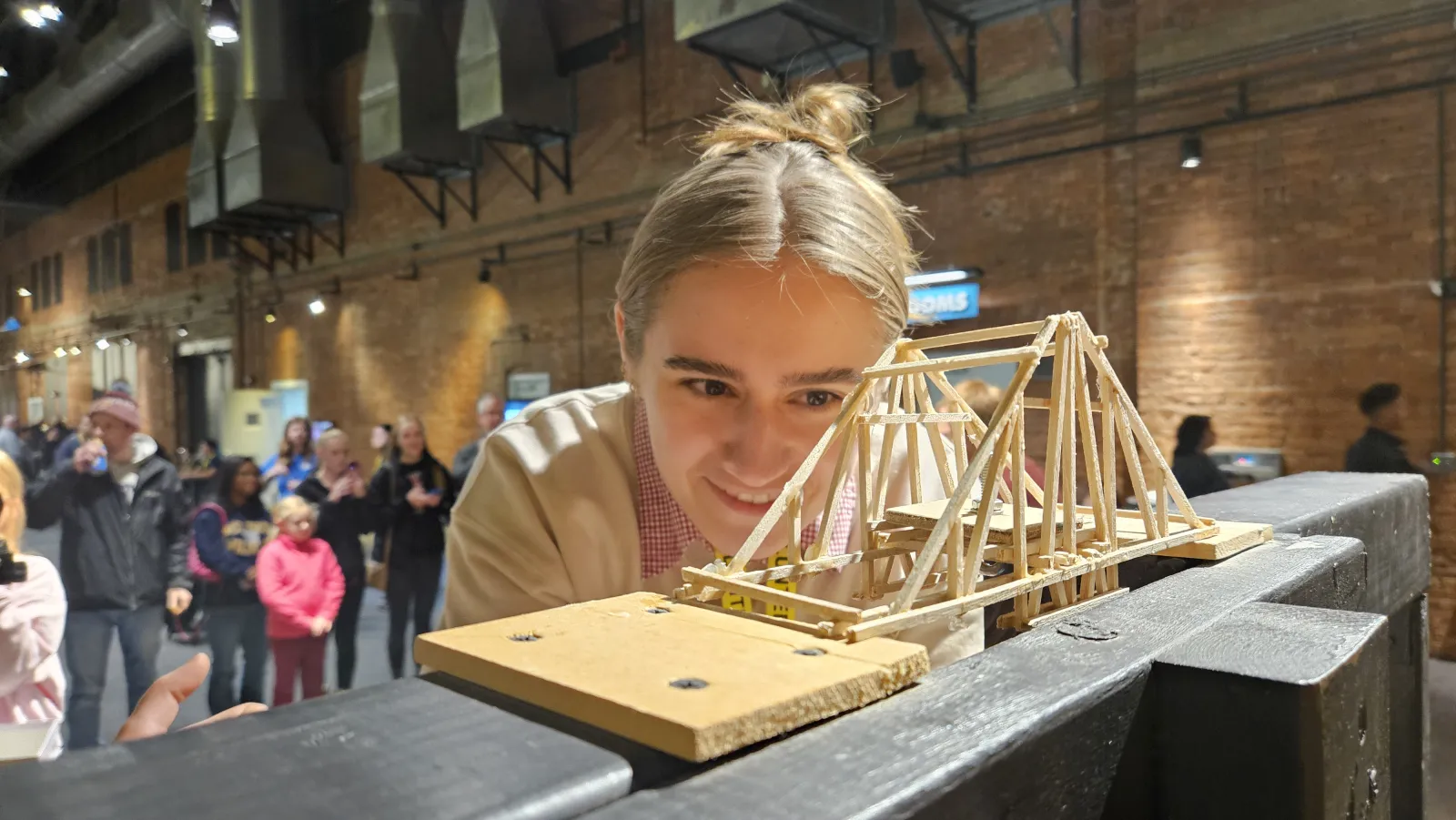 a student examines a wooden bridge at eye level on the test rig
