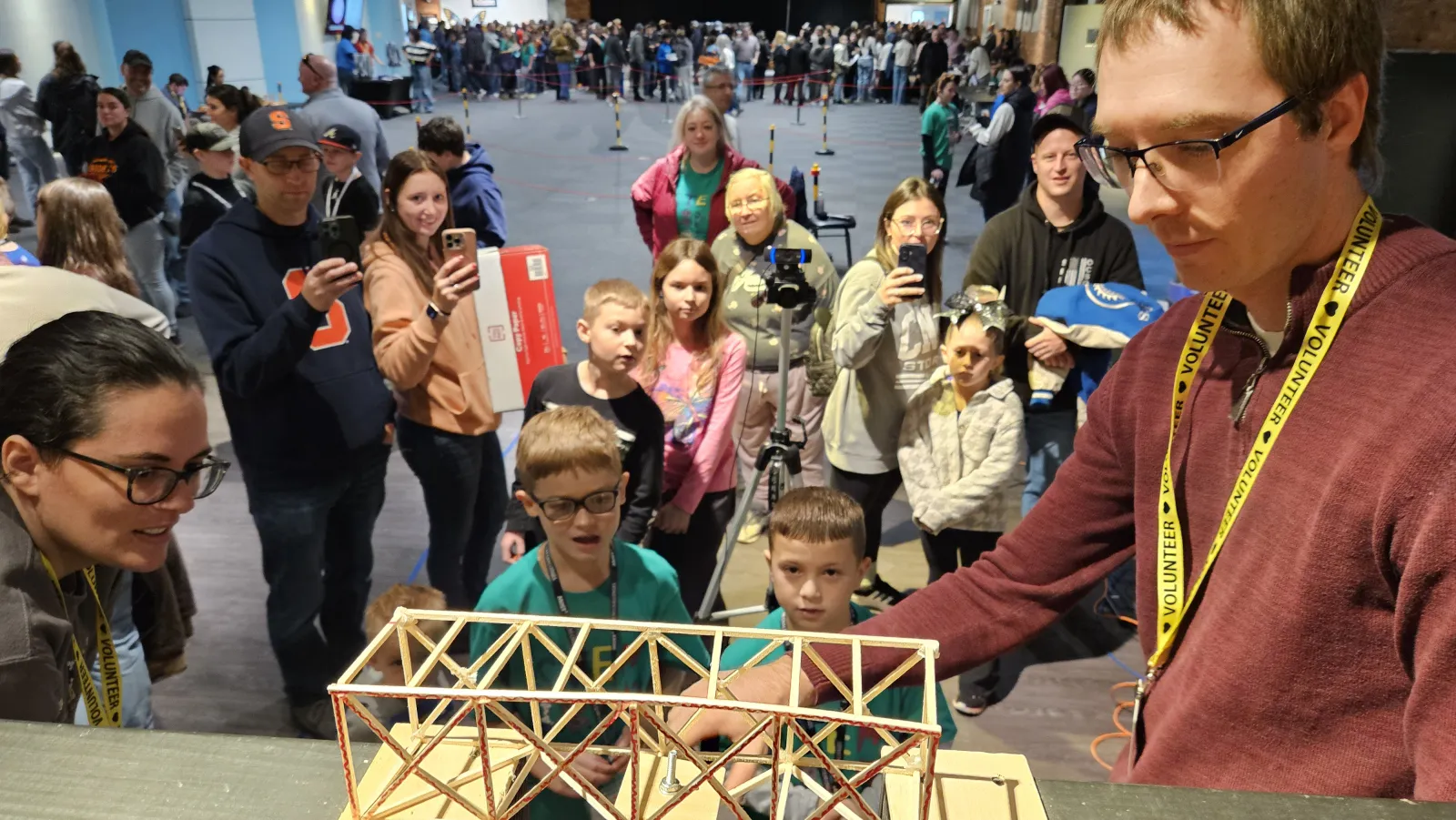 students watch a volunteer position their bridge in the testing frame