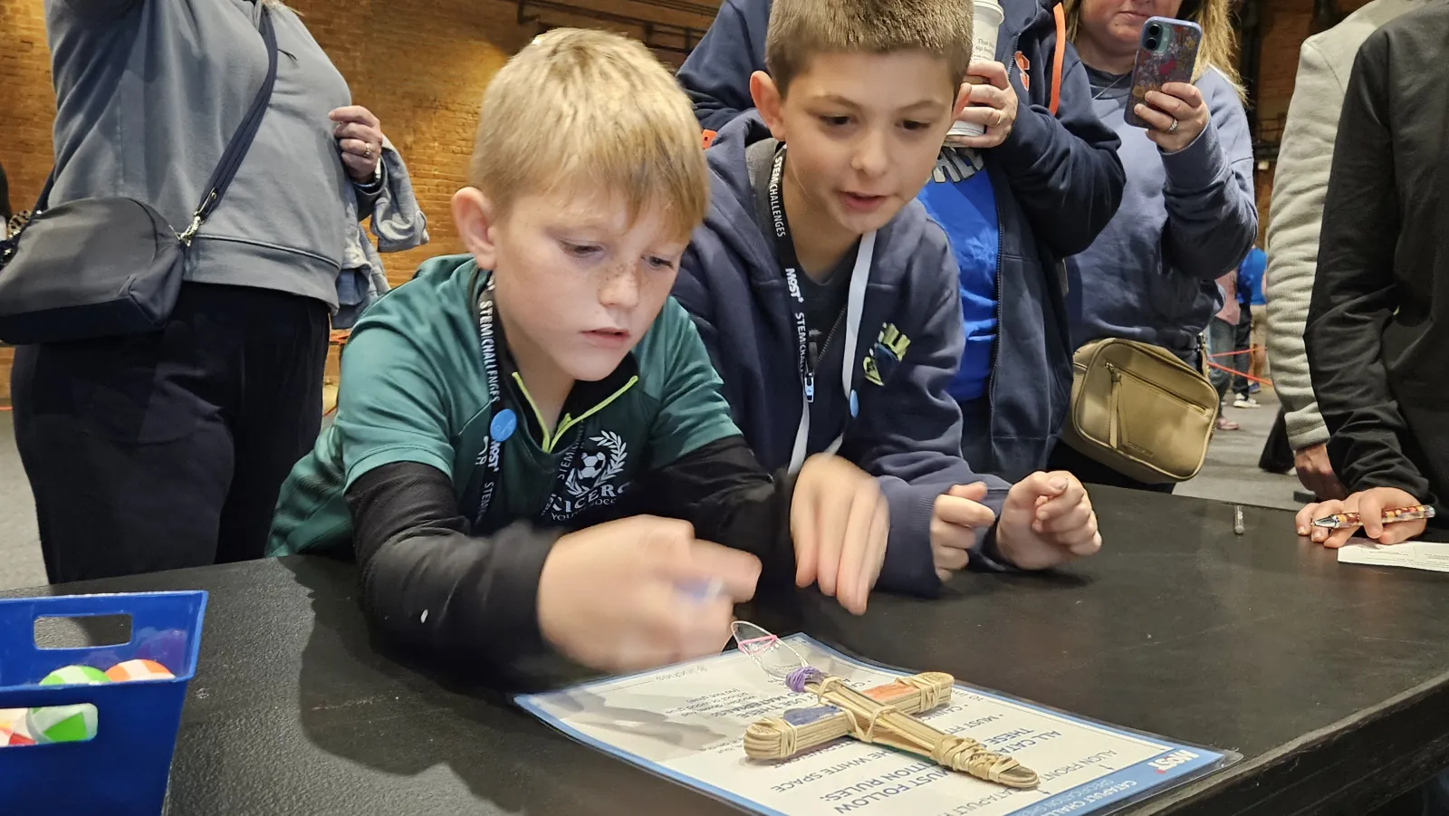 two students collaborate on a small catapult at the testing table